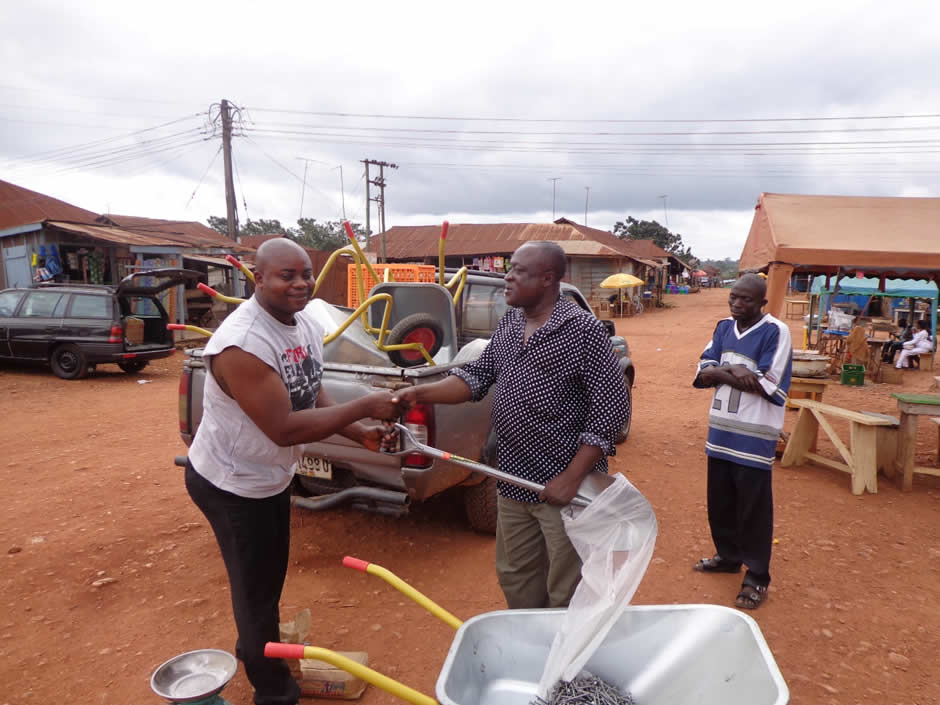 Two people shaking hands near wheelbarrows in a market area in Ghana